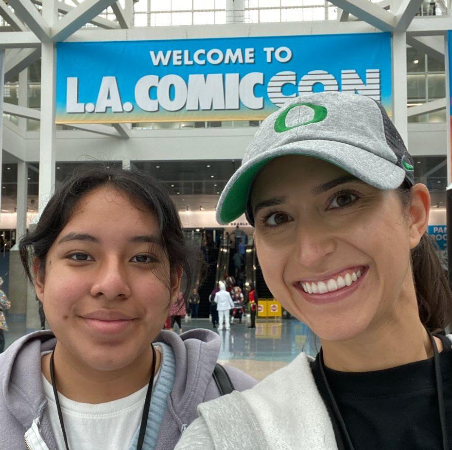 Latina teen and woman below LA ComicCon banner