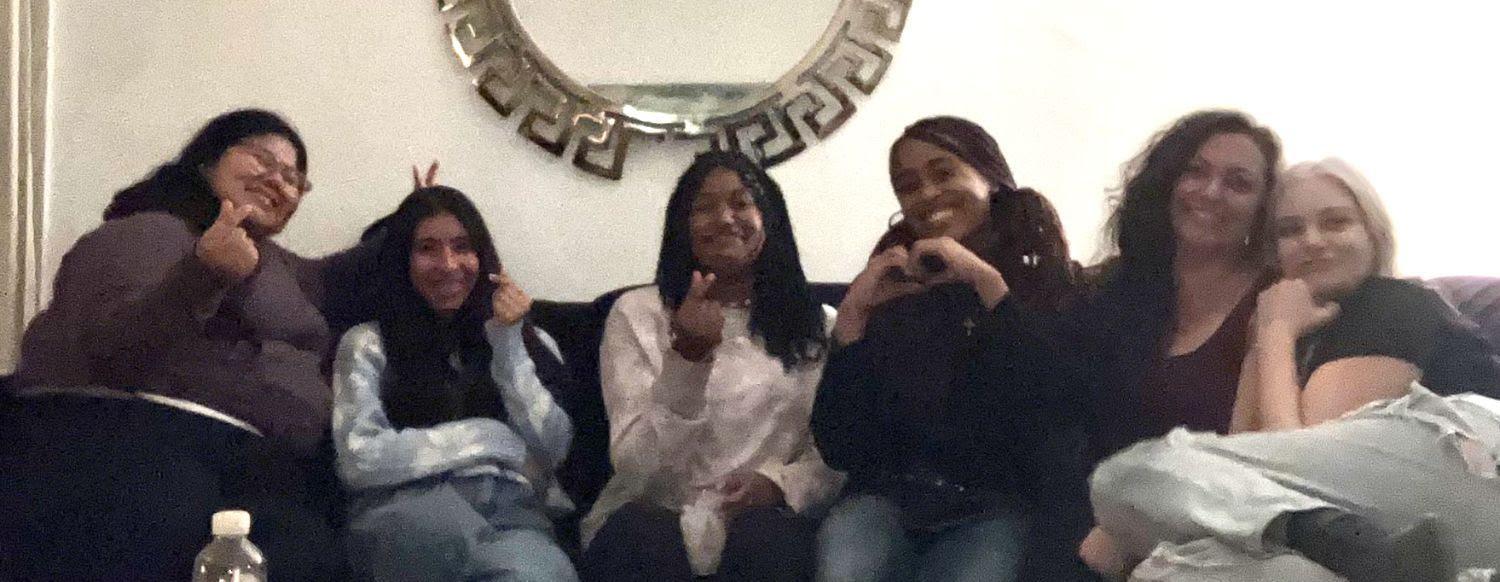 Four smiling diverse teens and two women on couch