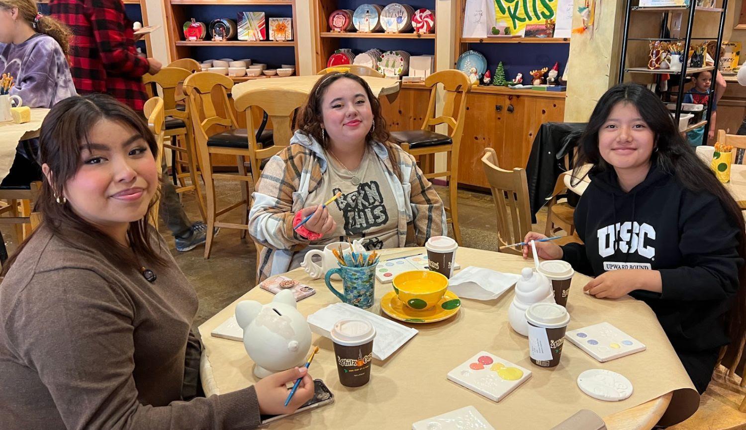 Three Latina girls painting pottery